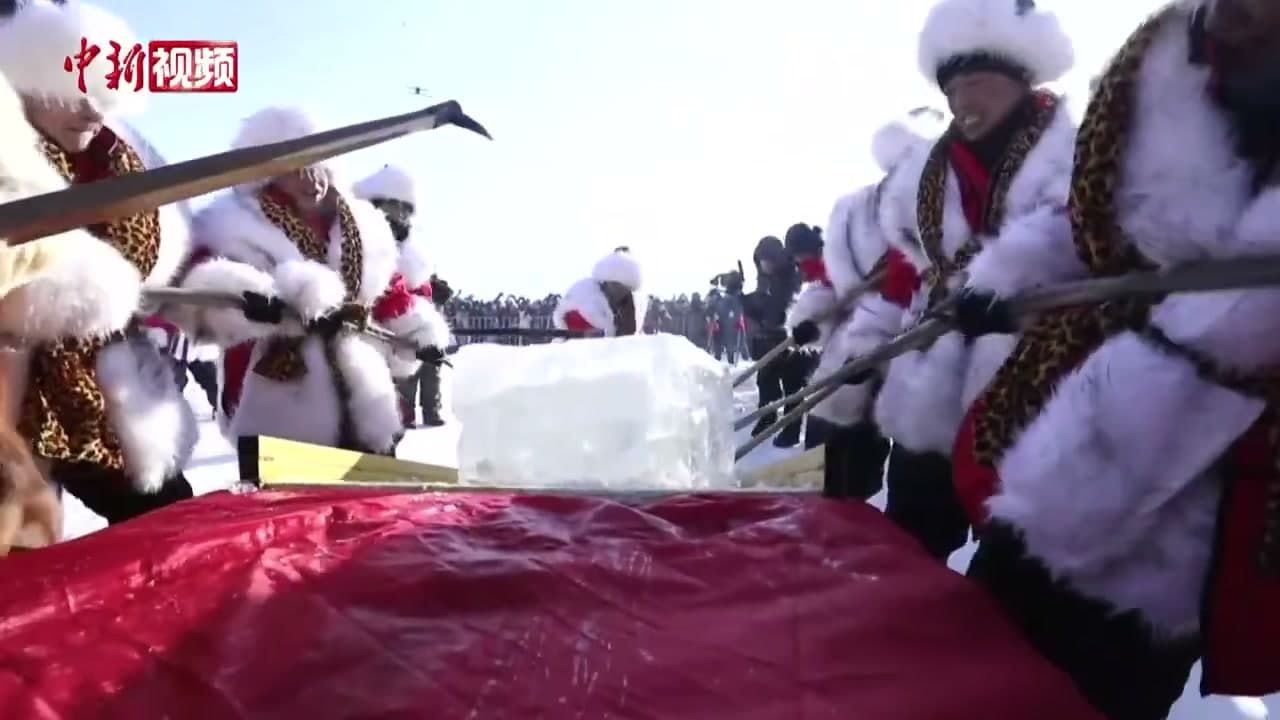 Festival participants using hooks to handle a cut block of ice in Harbin in 2020